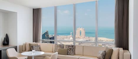 Habitació d'hotel moderna amb una finestra gran que ofereix vista a la ciutat, un sofà, una taula rodona petita i un llit.