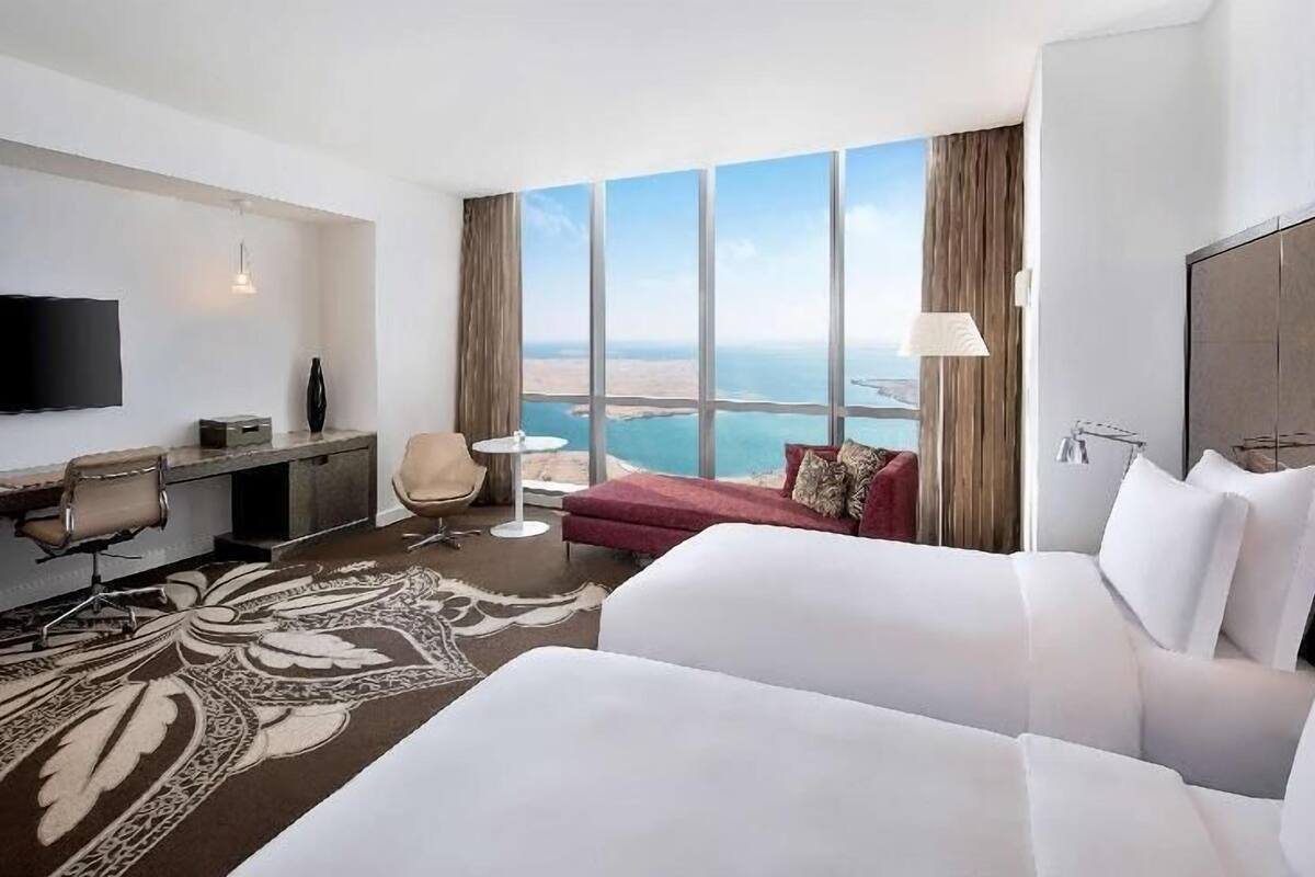 Habitación de hotel con una cama grande, un escritorio, una silla, un televisor y vista al océano.