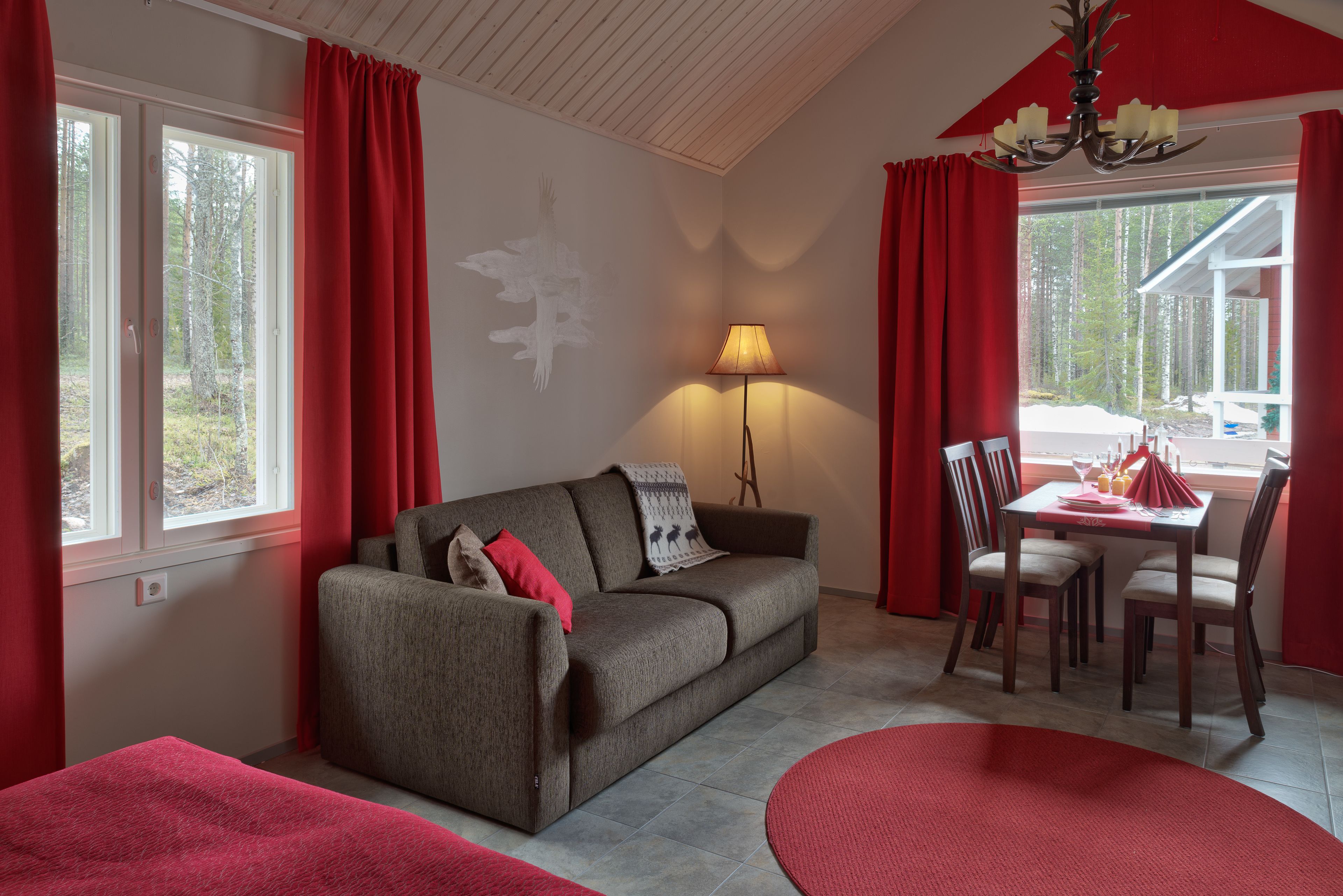 Une pièce confortable avec un canapé, une table à manger et des chaises, une lampe, et une vue sur l’extérieur.