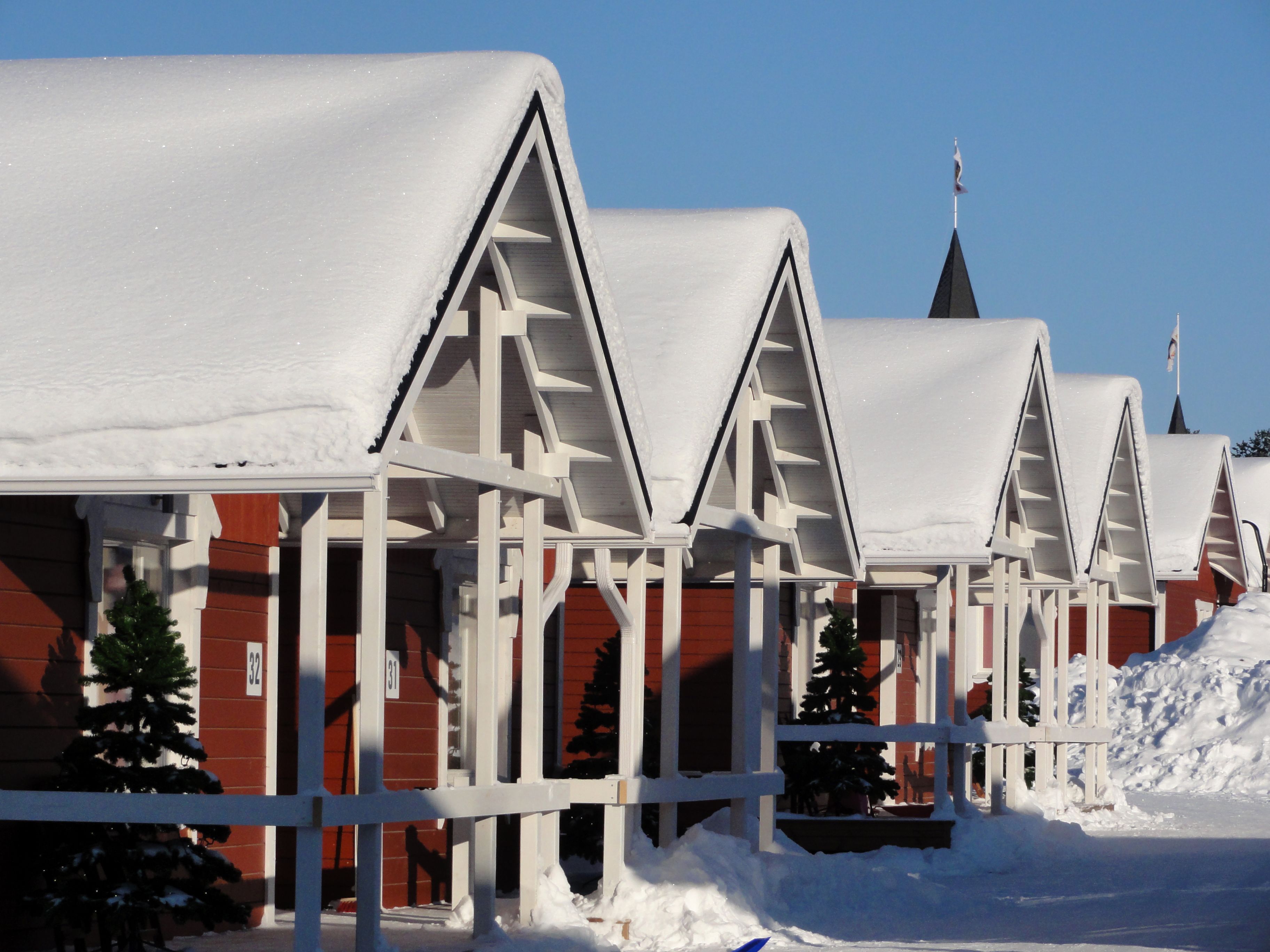 Una hilera de edificios cubiertos de nieve con un diseño de techo triangular característico, probablemente parte de un hotel o complejo turístico.