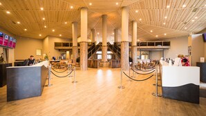 Eine geräumige Lobby mit Holzböden, einer zentralen Treppe und zwei Empfangstresen.