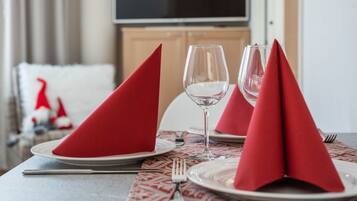 A dining table set with red napkins, wine glasses, and plates, with a patterned placemat and a fork on the table.
