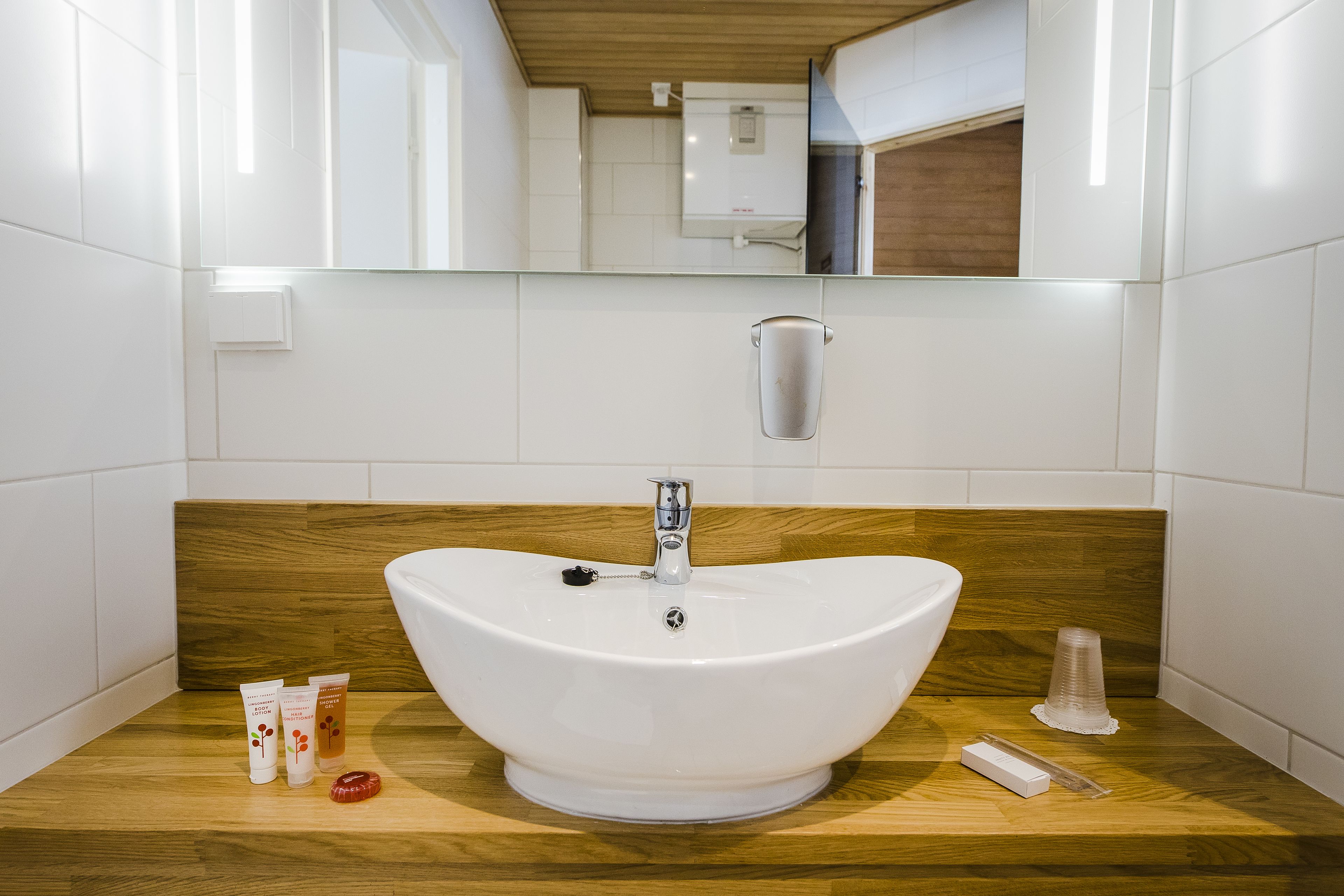 A modern bathroom with a white sink, wooden countertop, and a mirror above.