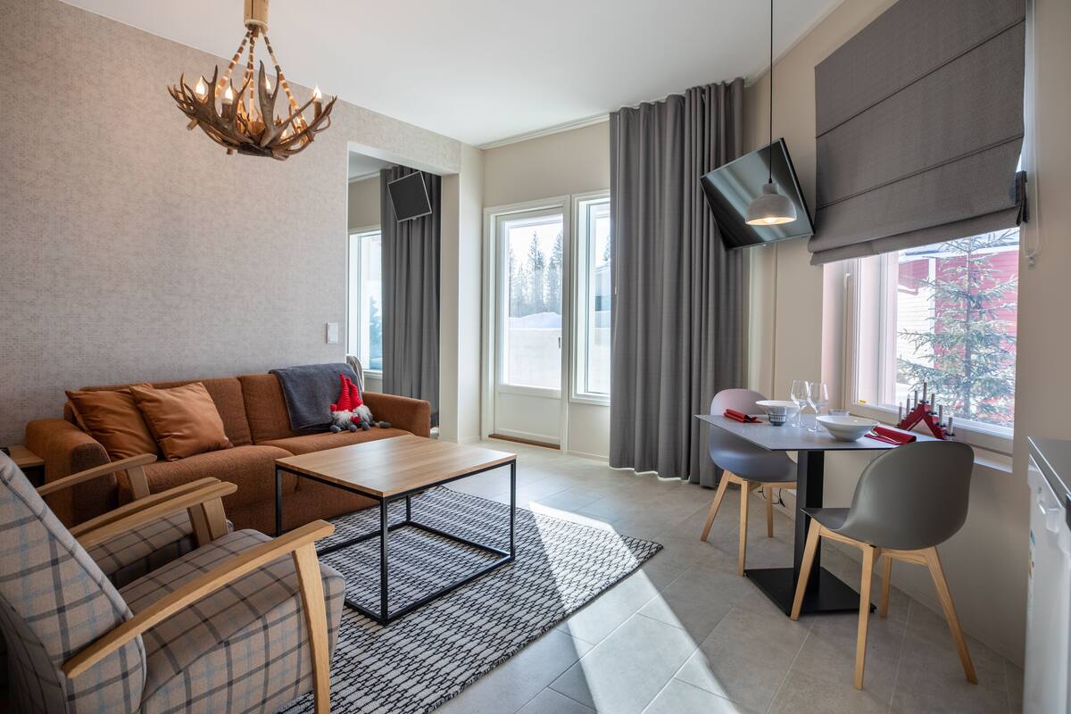 A modern living room with a sofa, coffee table, and dining area with chairs.