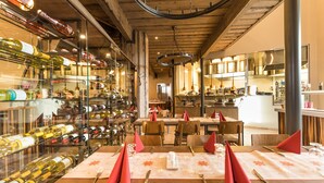 A restaurant with a wine cellar, wooden ceiling, and tables set for dining. - Santa Claus Holiday Village (Rovaniemi)