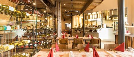 A restaurant with a wine cellar, wooden ceiling, and tables set for dining.