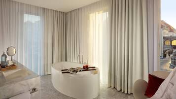 A modern bathroom with a freestanding bathtub, a vanity with a mirror, and a view of a cityscape through large windows.