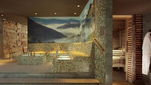 Un área de spa con paredes de piedra, un mural grande y una bañera de madera.