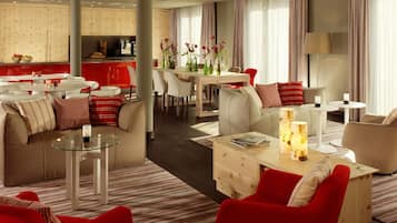 A modern hotel room with a dining area, a sofa set, and a coffee table.