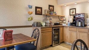 Una cocina con armarios de madera, lavavajillas, cafetera y diversos alimentos en los estantes.