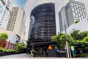 A modern hotel with a curved facade, a prominent entrance, and a sign indicating it is the Best Western. - Best Western Sukhumvit 20 (Bangkok)