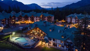 A lodge with multiple buildings, a swimming pool, and a mountainous backdrop. - Lizard Creek Lodge (Fernie)