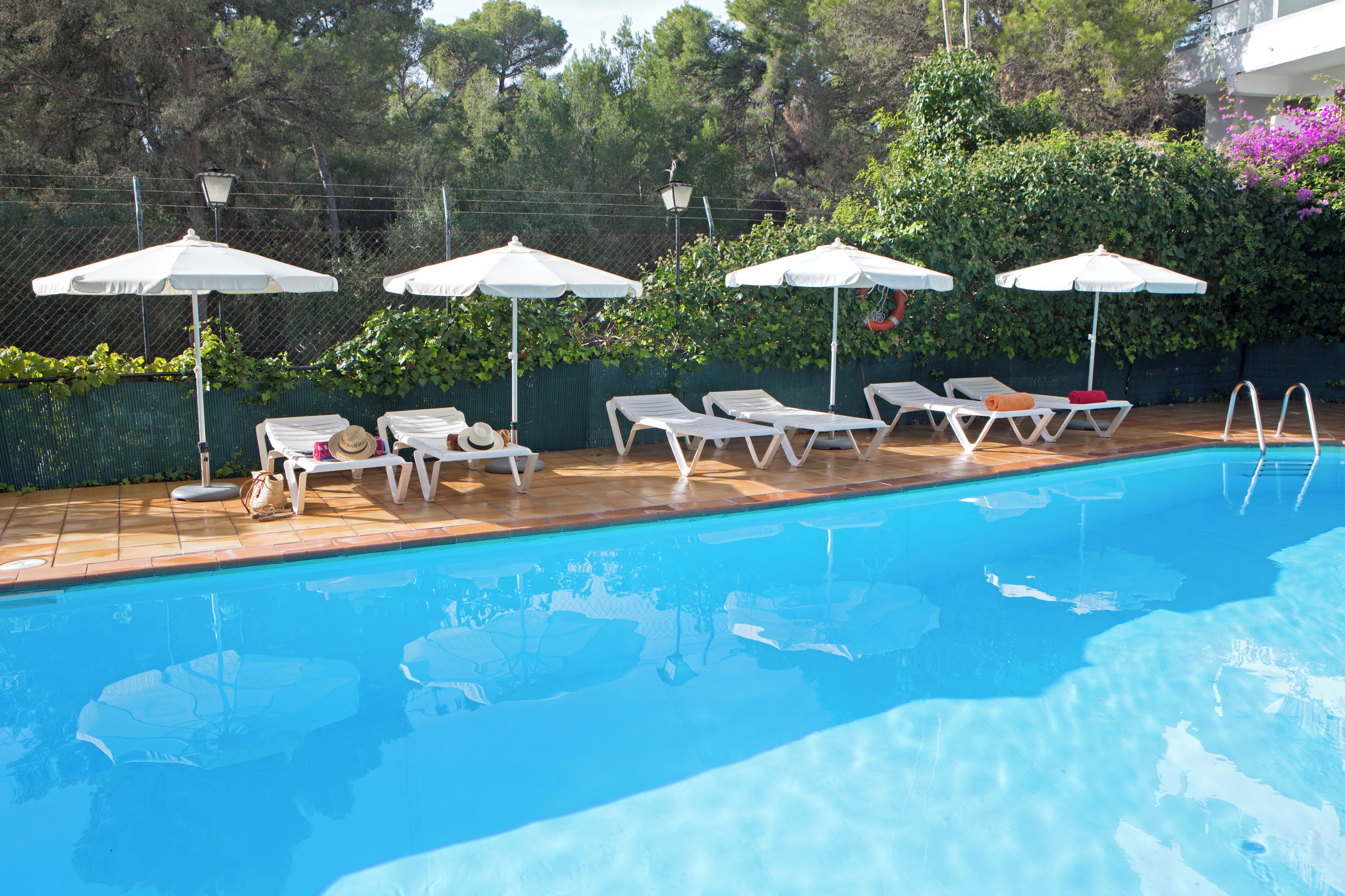 A swimming pool with lounge chairs and umbrellas.