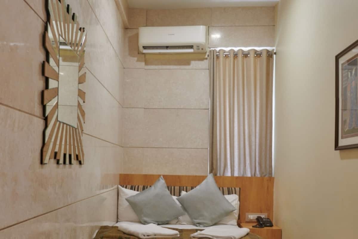 A bedroom with a bed, bedside table, and an air conditioning unit.
