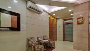 A reception area with striped chairs, a small table, and a wall-mounted air conditioner. - Bentley Hotel Marine Drive (Mumbai)