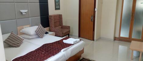 Habitación de hotel con cama, una silla, un armario y una mesita.