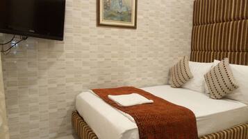 Una habitación de hotel con una cama, un televisor y un cuadro en la pared.