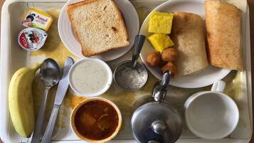 Una bandeja con diferentes alimentos para el desayuno, como tostadas, huevos revueltos, un plátano y una taza de té.