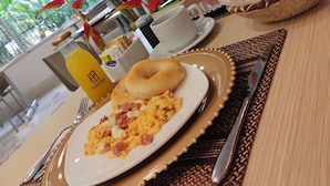 A breakfast setting with scrambled eggs, a bagel, and a bottle of orange juice on a table.