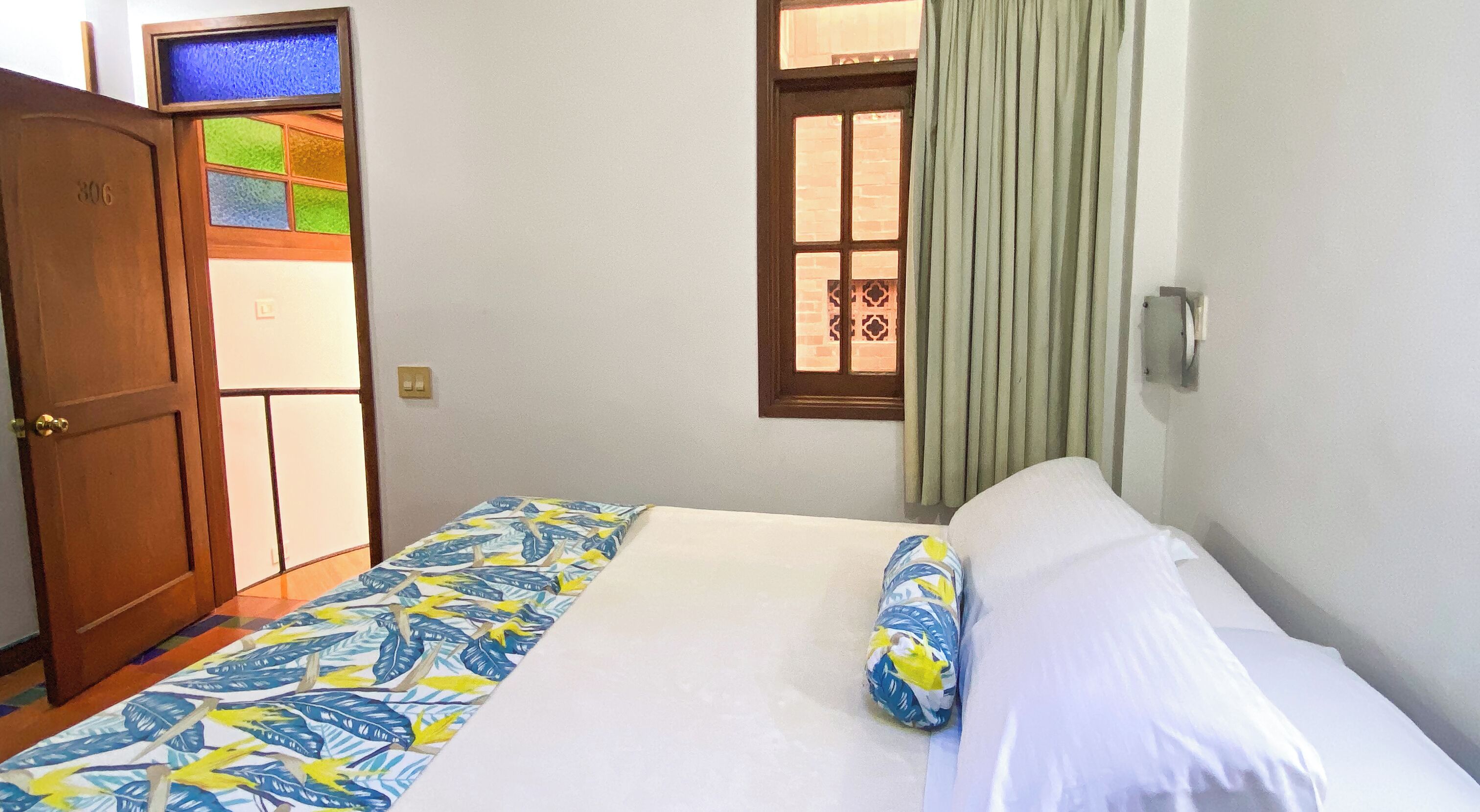 A room with a bed, a door, and a window with curtains.