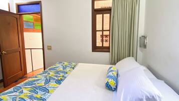 A room with a bed, a door, and a window with curtains.