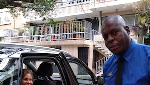A black car with a checkered pattern on the door, parked in front of a building with a balcony.