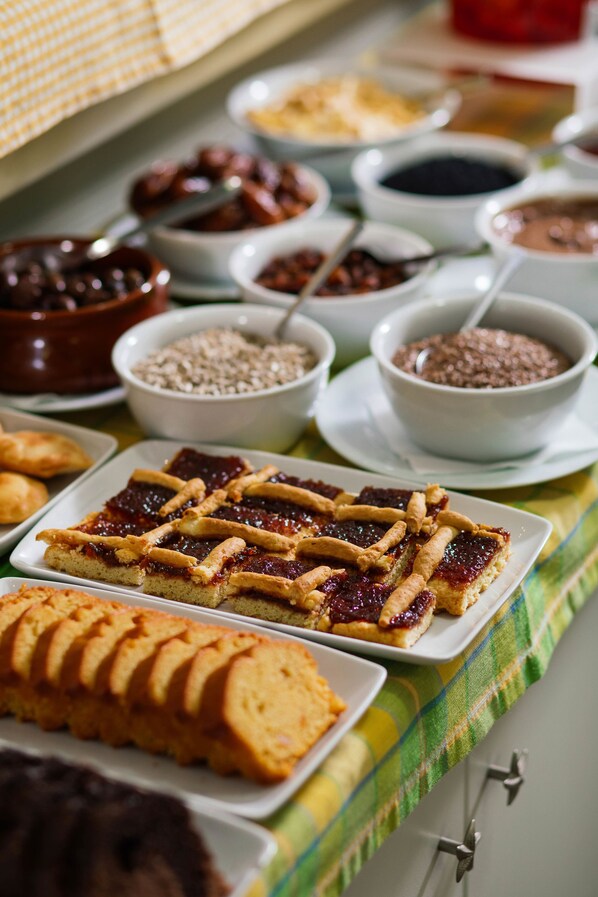 Una mesa de buffet con diversos platos, incluyendo un postre con cubierta de celosía, un pastel en capas y varios recipientes con salsas y condimentos.