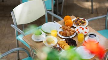 Une table de petit-déjeuner avec des croissants, du jus d’orange et du café.
