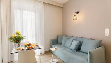 A modern living room with a sofa, a dining table with breakfast, and a wall-mounted light.