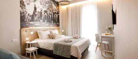 Une chambre d’hôtel moderne équipée d’un lit, d’une table de chevet, d’une lampe et d’un bureau avec une chaise.