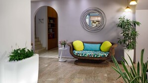 A modern interior with a sofa, a mirror, and a potted plant. - Sofia Hotel (Agios Vasileios)