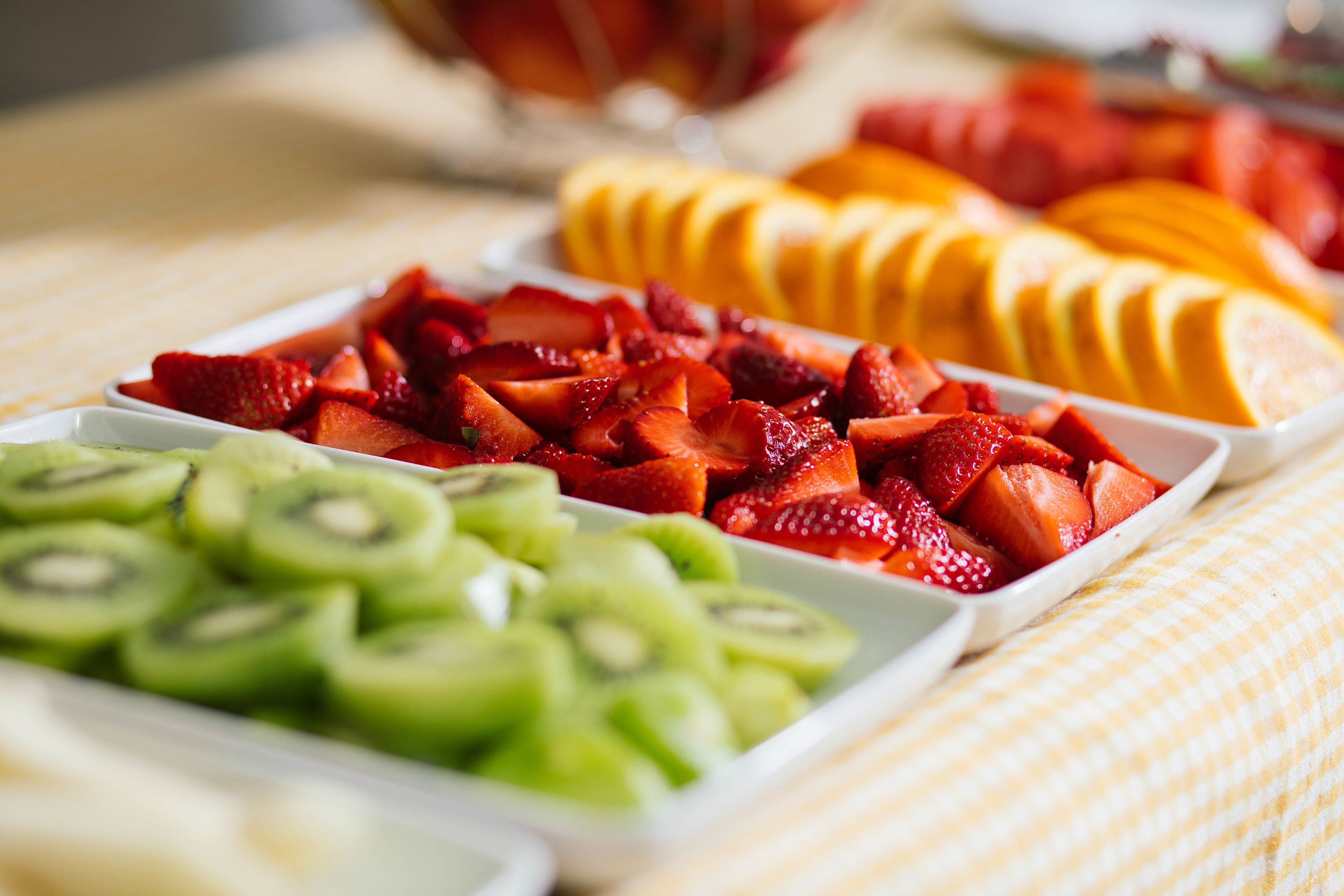 Un bufé con frutas cortadas, entre ellas fresas, kiwi y mango.