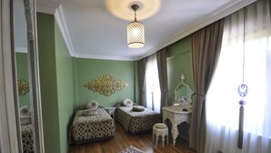 Une chambre avec deux lits à motifs, un élément décoratif mural, un luminaire suspendu et une table traditionnelle.