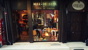 Un bâtiment à la façade verdoyante et doté de nombreuses fenêtres. Le rez-de-chaussée abrite une boutique dont l’enseigne indique : « MAR DE SEDA BY FINITO DE CORDOBA ».