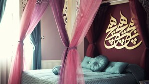 Une chambre à coucher avec un lit, un baldaquin et un mur orné de calligraphies arabes.