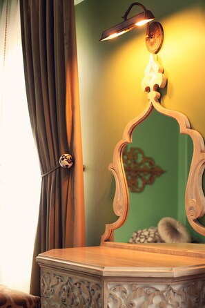A wooden vanity with a mirror, a wall-mounted light fixture, and a decorative wall piece. - Kervan Hotel (Istanbul)