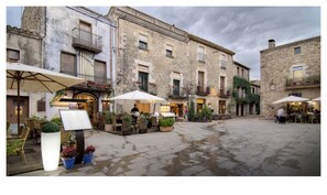 A courtyard with outdoor seating, stone buildings, and a wet ground. - Hotel Aatu - Adults Only (Forallac)