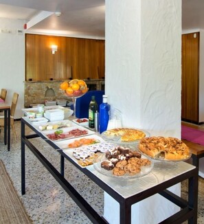 Buffet amb diversos aliments, com ara fruita, formatges, carns i postres.