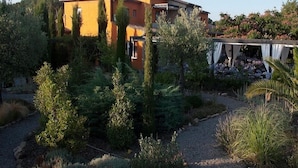 Una villa de estilo mediterráneo con jardín, pérgola y un camino de piedra.