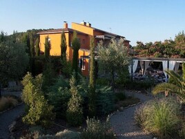 Una villa de estilo mediterráneo con jardín, pérgola y un camino de piedra.