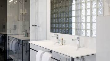 A modern bathroom with a glass shower enclosure, a large mirror, and a white vanity.