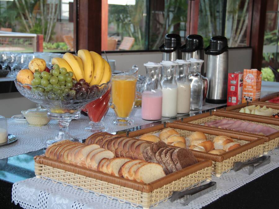 A buffet with various food items including fruits, bread, and beverages.