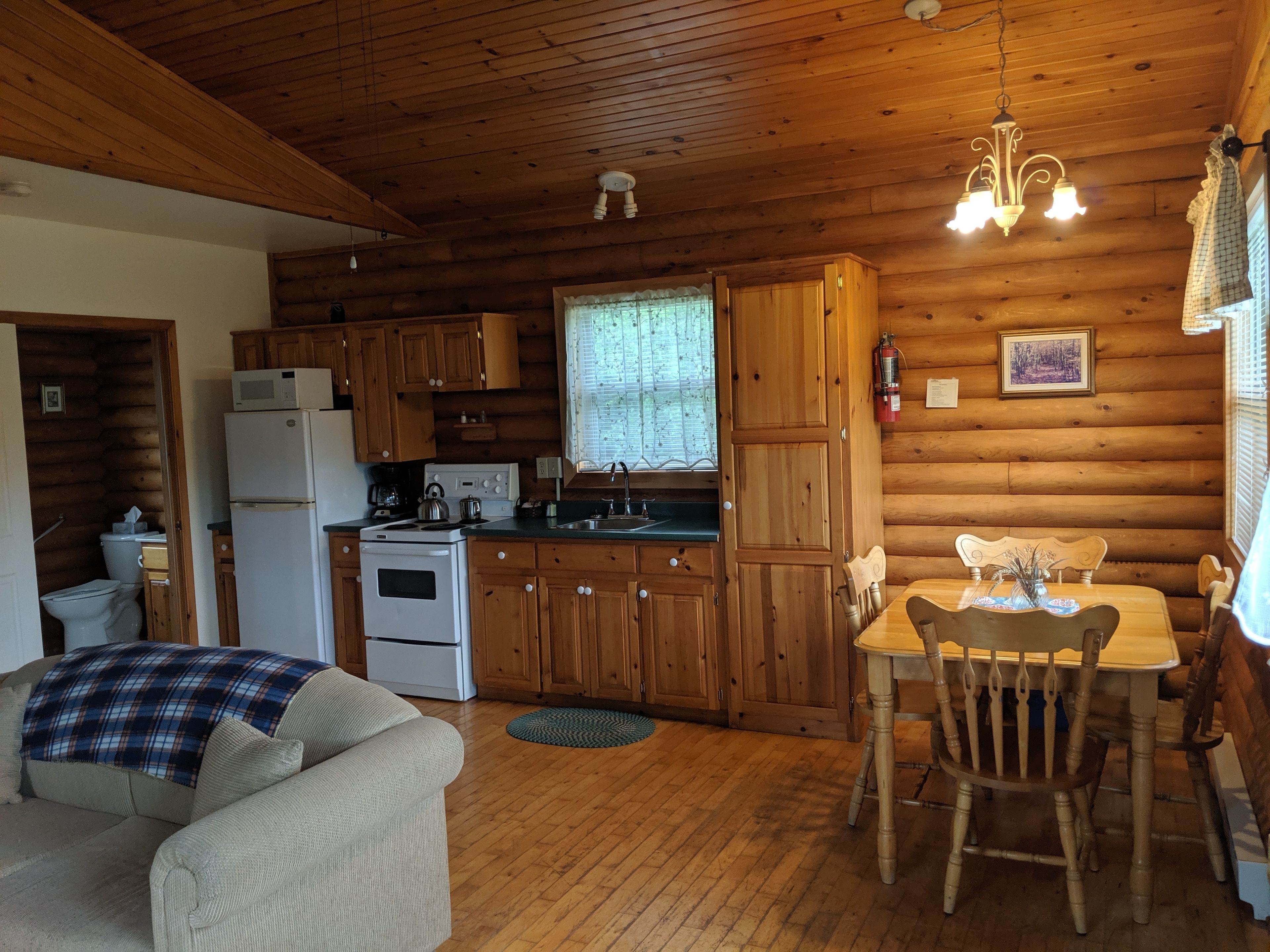 A cozy cabin-style kitchen with wooden walls and a dining area.