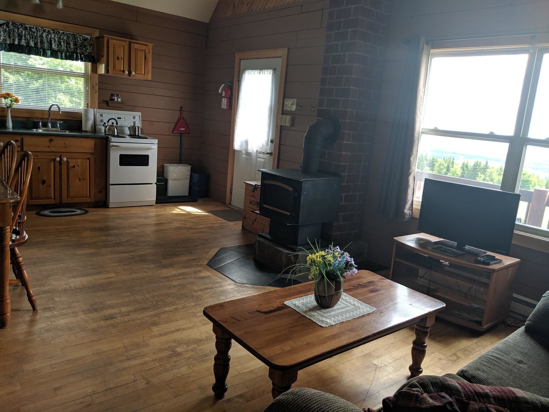 A cozy living room with a fireplace, a television, and a dining area with wooden furniture.