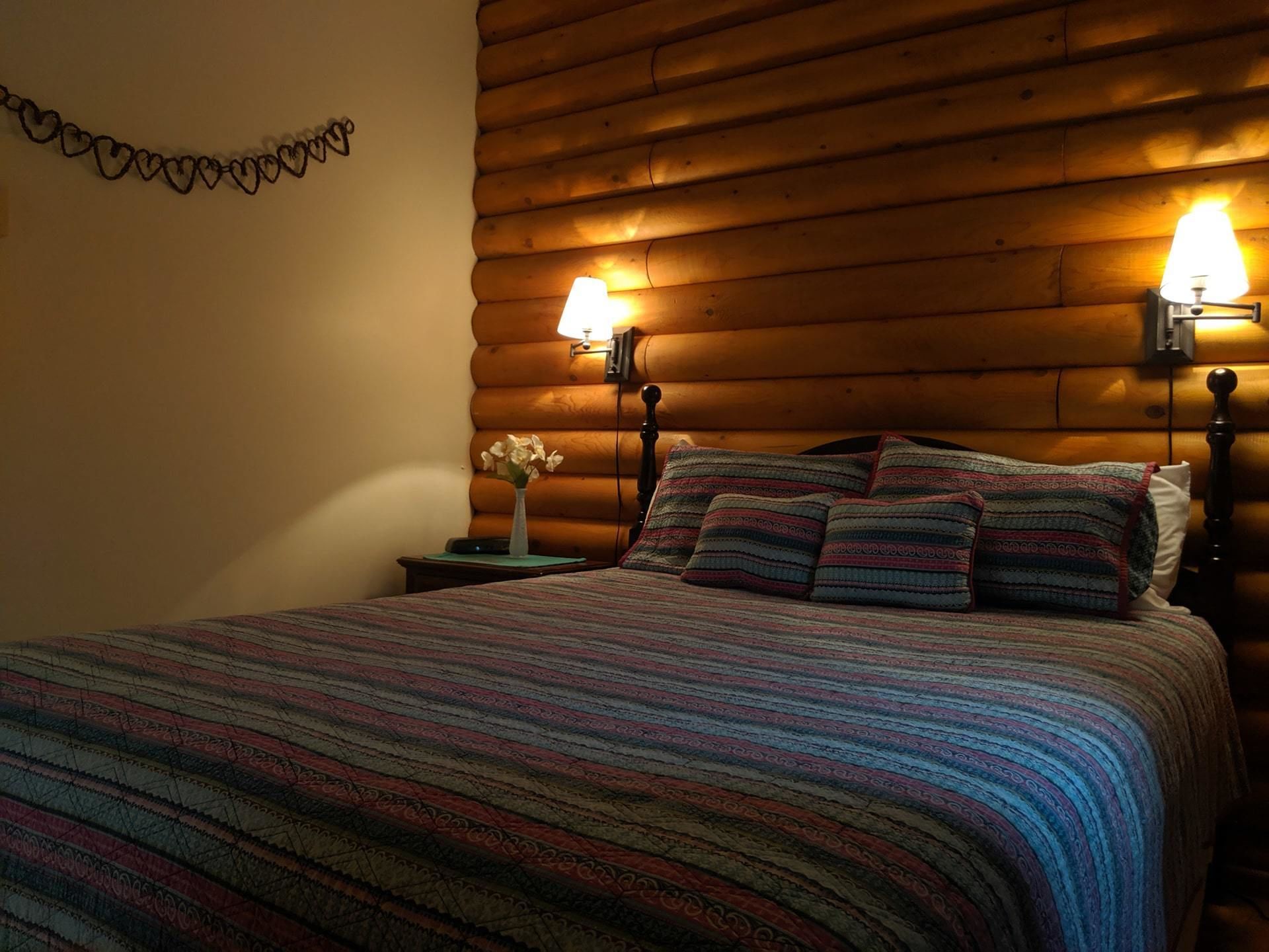 Une chambre confortable avec une tête de lit en bois, une couvre-lit à rayures et deux lampes de chevet.