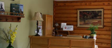 A reception desk with a Canada Select sign, a lamp, a framed painting, and a vase with flowers.