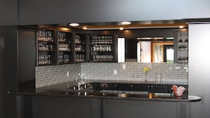 Una cocina moderna con armarios oscuros, una isla central con pileta y estanterías de vidrio empotradas para vajilla.