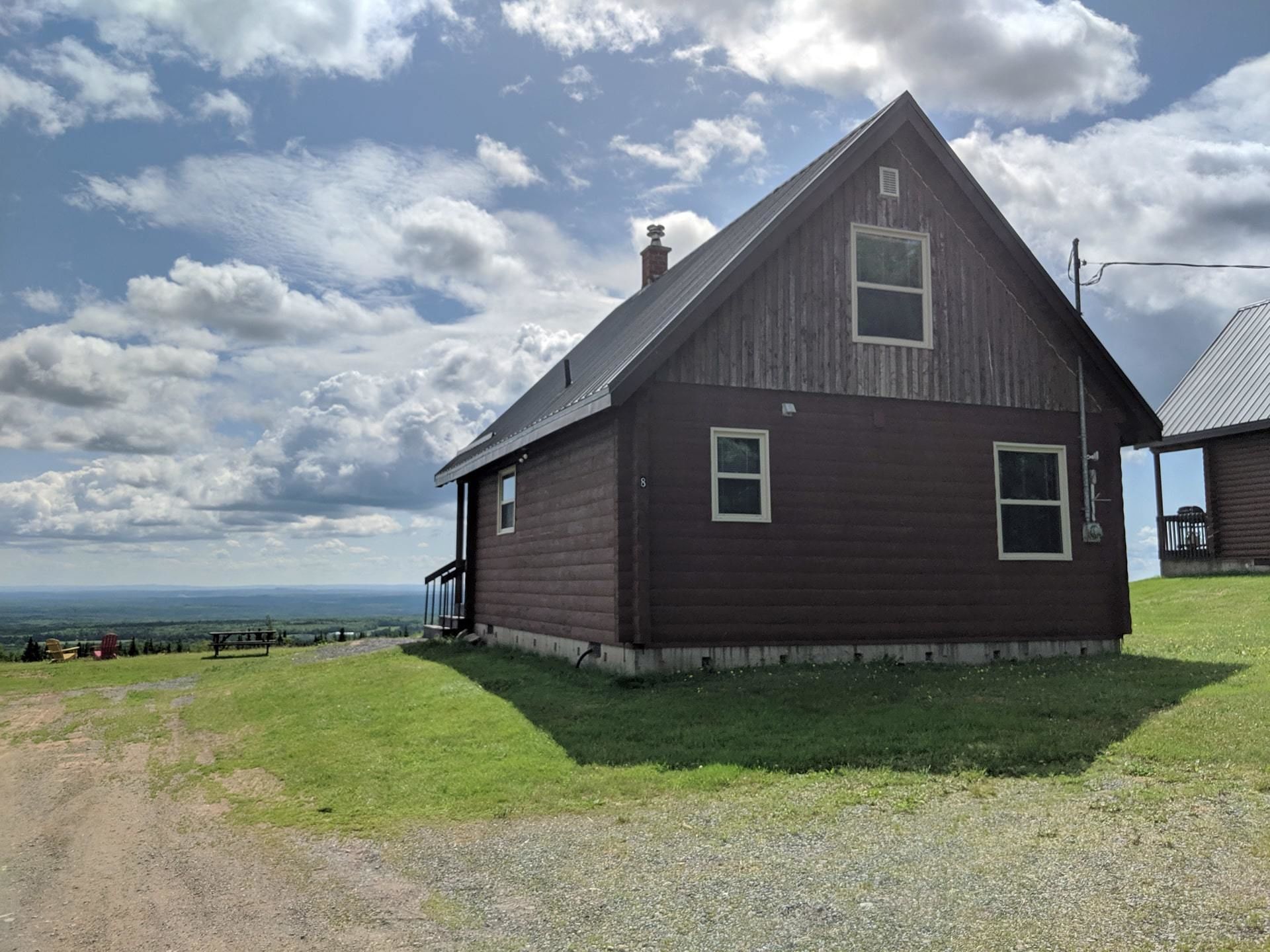 A wooden house with a gabled roof, a chimney, and a porch.