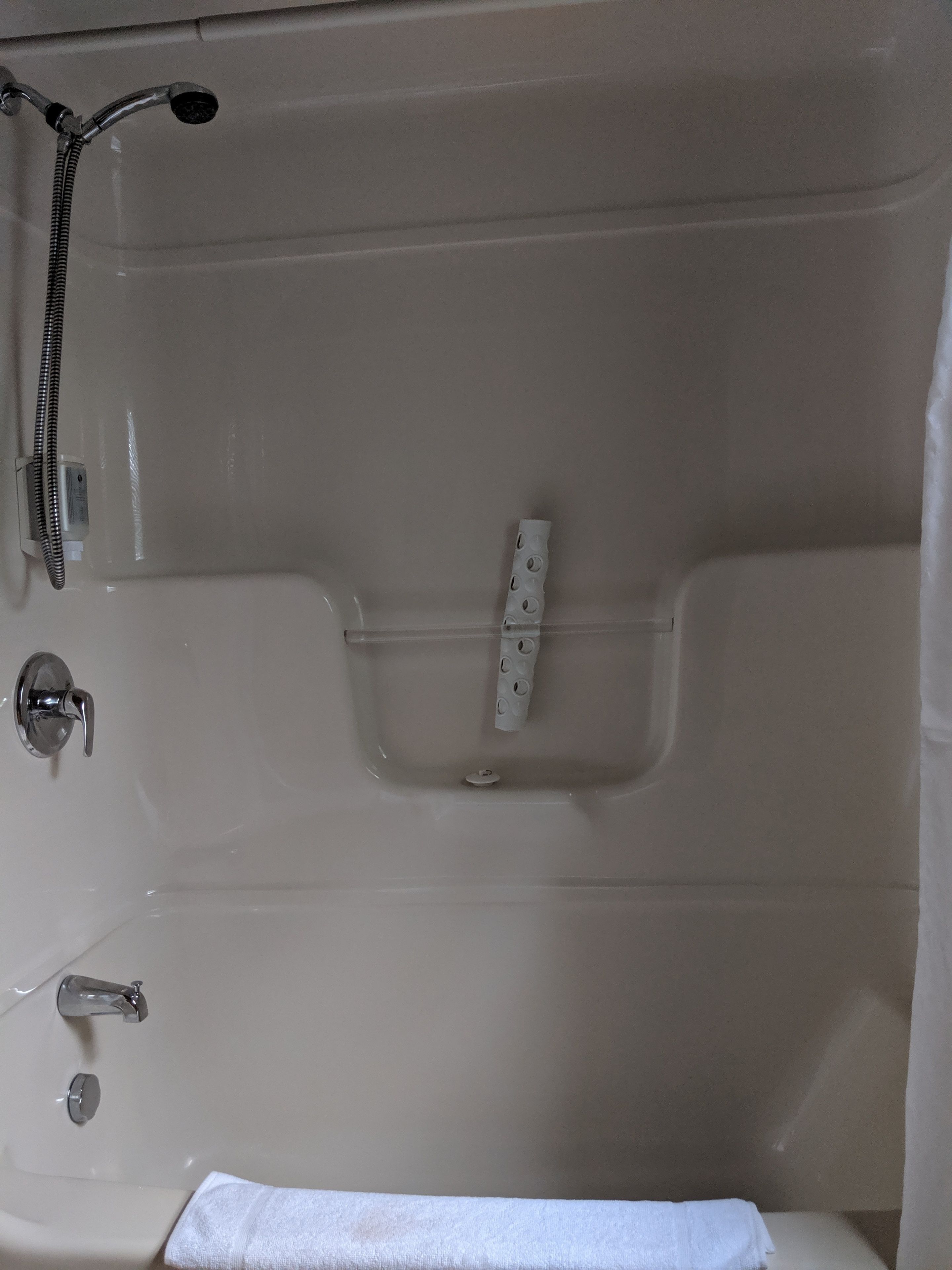 Una bañera con un cabezal de ducha, un panel de control y una toalla.