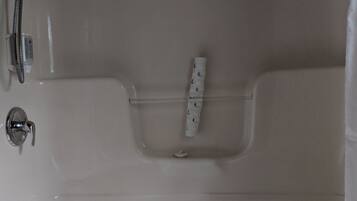 Una bañera con un cabezal de ducha, un panel de control y una toalla.